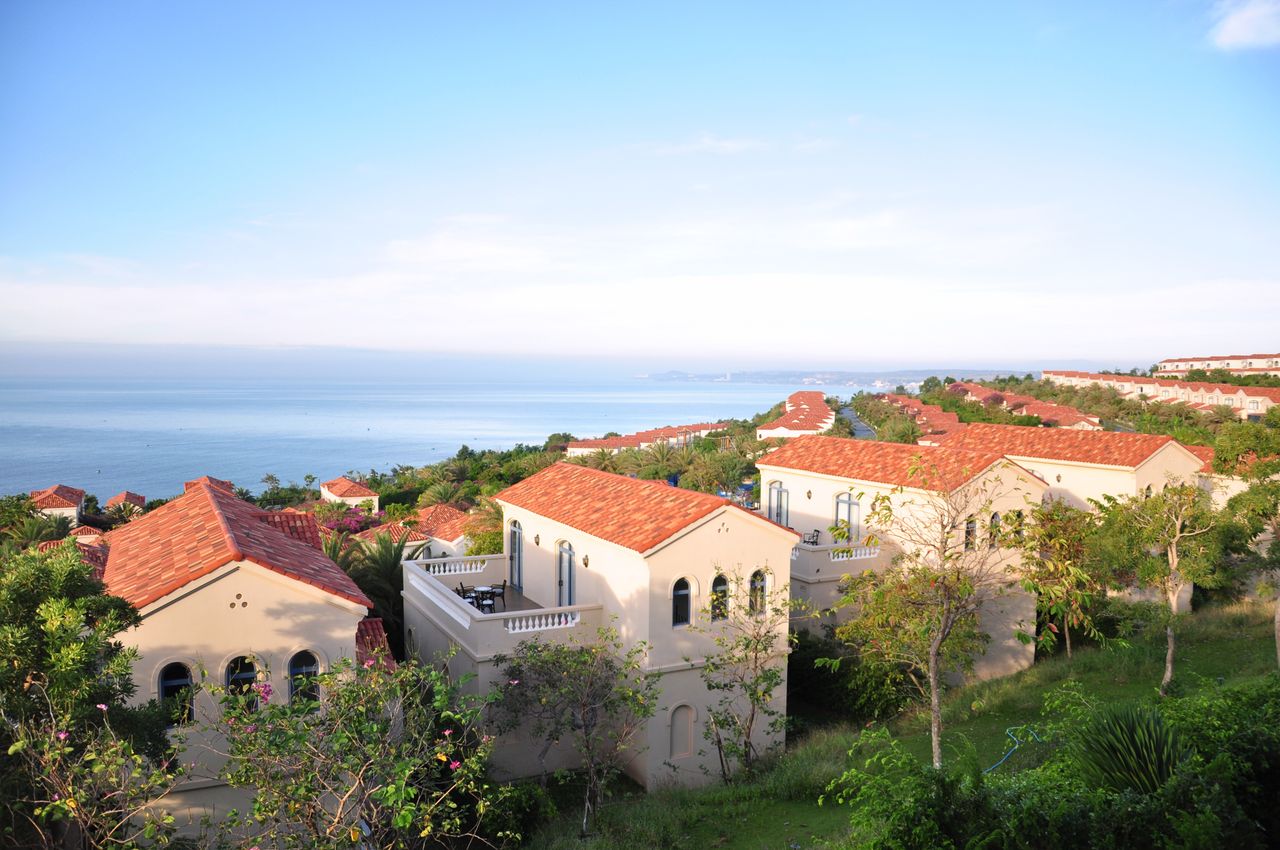 expertise-01 Beautiful Mediterranean villas overlooking a tranquil sea under clear skies.